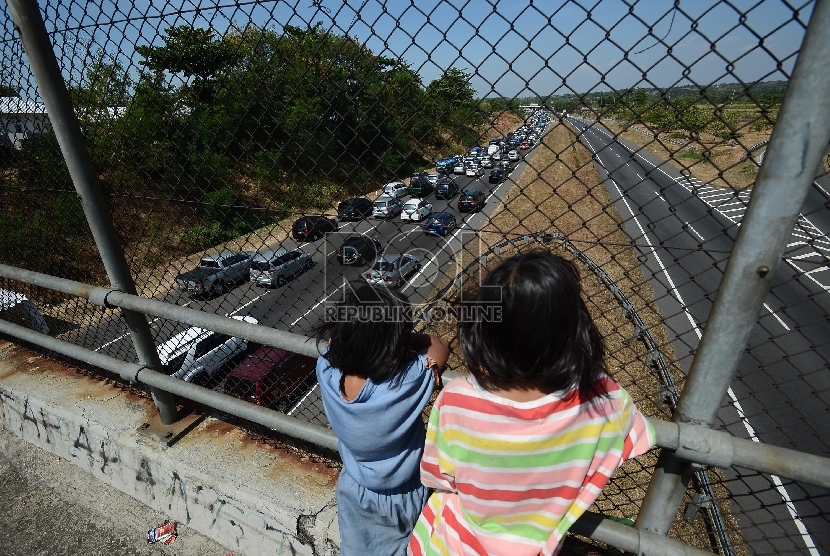 Dua orang anak menonton ribuan kendaraan yang terjebak kemacetan di ruas Jalan Tol Palimanan-Kanci KM 204 hingga gerbang tol Palimanan KM 188 Jalan Tol Cipali, Cirebon, Jawa Barat.