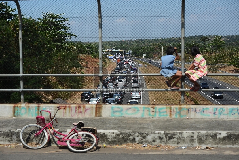 Dua orang anak menonton ribuan kendaraan yang terjebak kemacetan di ruas Jalan Tol Palimanan-Kanci KM 204 hingga gerbang tol Palimanan KM 188 Jalan Tol Cipali, Cirebon, Jawa Barat, Rabu (15/7).