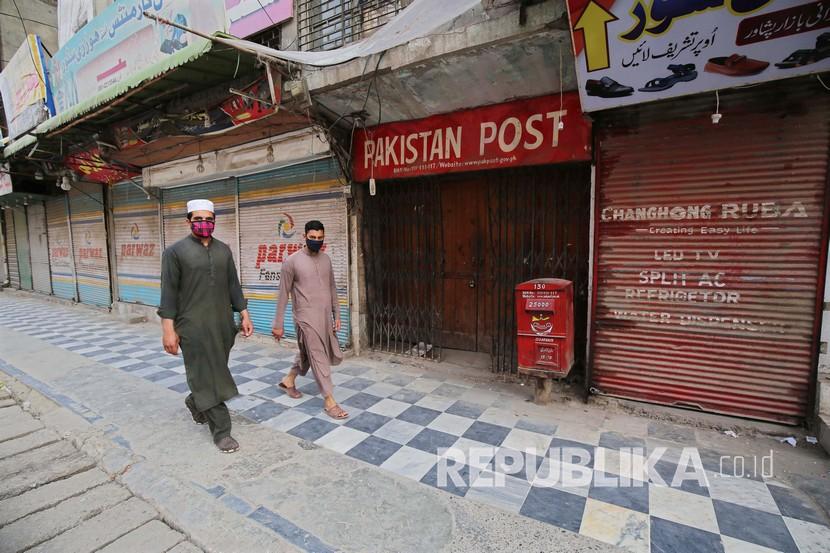 Dua orang berjalan di depan toko yang tutup selama pembatasan karena COVID-19 di Peshawar, Pakistan, Jumat (15/5). Pemerintah provinsi Punjab, Sindh, Khyber Pakhtunkhwa dan Balochistan pada Jumat (8/5) mengumumkan peloggaran pambatasan wilayah. Pembatasan wilayah dilakukan sebagai upaya untuk menekan penyebaran Covid-19. 