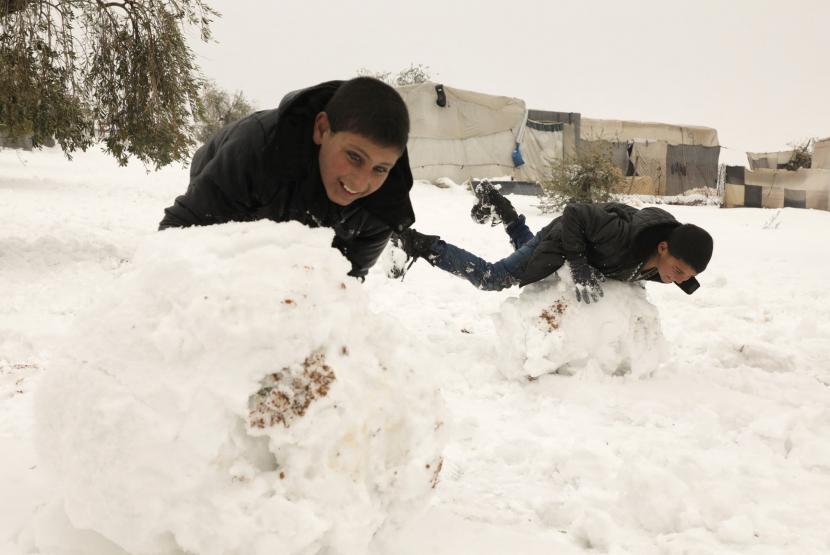 Dua orang bocah bermain bola salju di kamp pengungsi di Aleppo, Suriah, 23 januari 2022. Salju Selimuti Timur Tengah