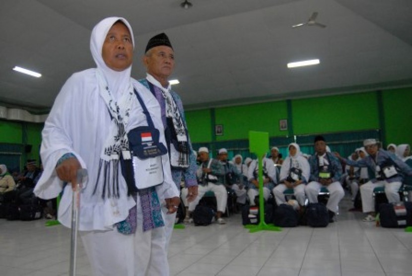 Dua orang calon haji kelompok terbang (kloter) pertama berjalan bersama ketika tiba di Asrama Haji Sukolilo, Surabaya, Jawa Timur, Kamis (20/8). 