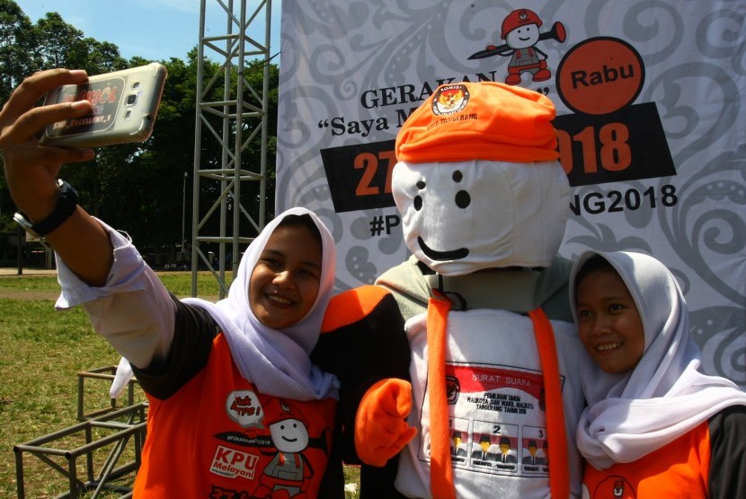 Dua orang calon pemilih pemula berswafoto dengan maskot Pilkada Kota Tangerang yang bernama Si Bentos usai launching tahapan Pilkada Serentak Kota Tangerang di Tangerang, Banten, Senin (20/11). 