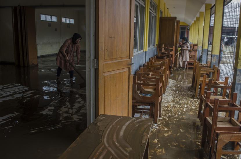 Dua orang guru membersihkan ruangan kelas yang terendam lumpur akibat banjir bandang Sungai Cimanuk di Sekolah PGRI Garut, Jawa Barat, Sabtu (16/7/2022). Banjir bandang akibat luapan Sungai Cimanuk saat intensitas curah hujan yang tinggi pada Jumat (15/7) kemarin mengakibatkan sejumlah sekolah hingga rumah ibadah rusak berat. 