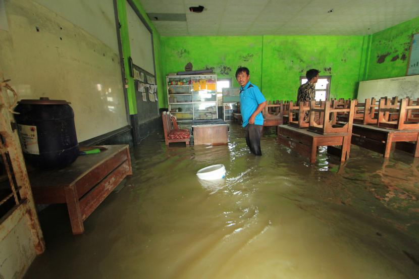 Dua orang guru menyelamatkan barang di ruang kelas yang terendam banjir (ilustrasi)