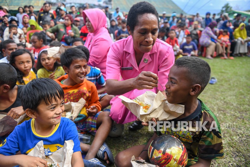Dua orang Ibu Bhayangkari menyuapi makan pada bocah pengungsi di Posko pengungsian di Makodim 1702/Jayawijaya, Wamena, Papua, Selasa (8/10/2019).