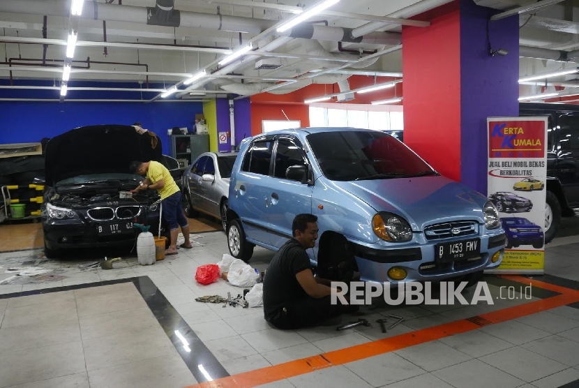 Dua orang mekanik sedang mengecek kondisi mobil yang sedang dipajang di showroom mobil bekasnya di bilangan Kemayoran Jakarta, Selasa (3/10).