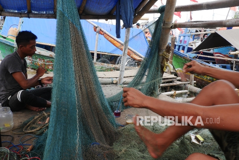 Dua orang nelayan memperbaiki jaring penangkap ikannya yang robek dan terkoyak di kampung nelayan Cilincing Jakarta, Kamis (12/1). 