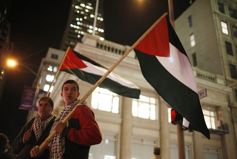 Dua orang pemuda mengibarkan bendera Palestina saat berunjuk rasa mengutuk serangan Israel terhadap warga sipil Gaza di luar gedung Konsulat Israel di San Francisco, California, Kamis (15/11). (Reuters/Stephen Lam)