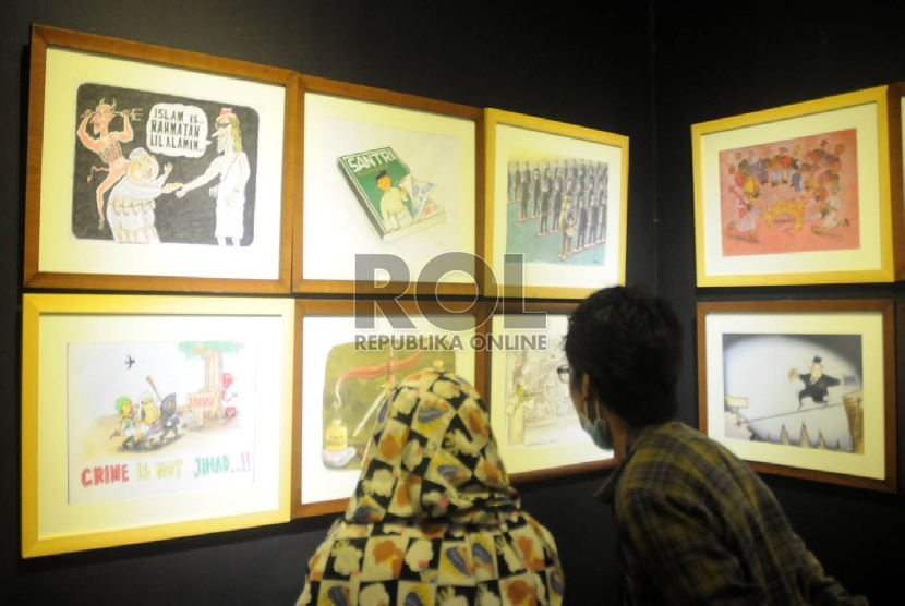 Dua orang pengunjung memperhatikan karya kartun, pada pameran Kartun Santri Nusantara di Galeri Nasional Jakarta, Kamis (26/11).