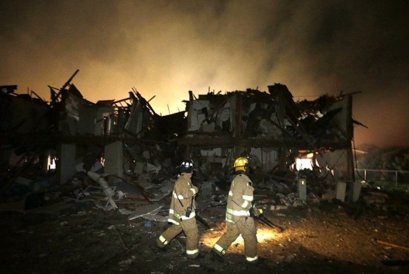 Dua orang perugas pemadam kebakaran tengah memeriksa sebuah apartemen di dekat satu pabrik pupuk yang meledak. Foto ini diambil pada Kamis (18/4) dini hari waktu setempat