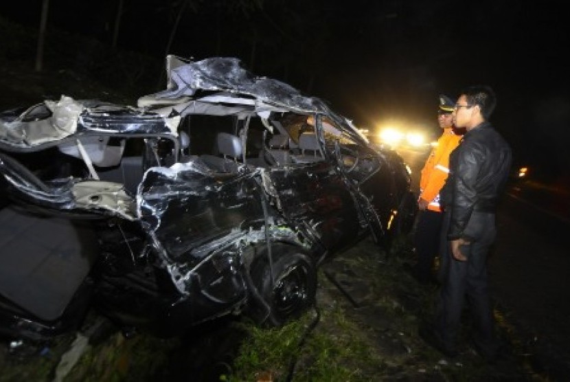 Dua orang petugas melihat bangkai mobil Kijang yang mengalami kecelakaan dengan bus pariwisata di di Tanjakan Emen, Kabupaten Subang, Jawa Barat, Selasa (17/6) malam. 