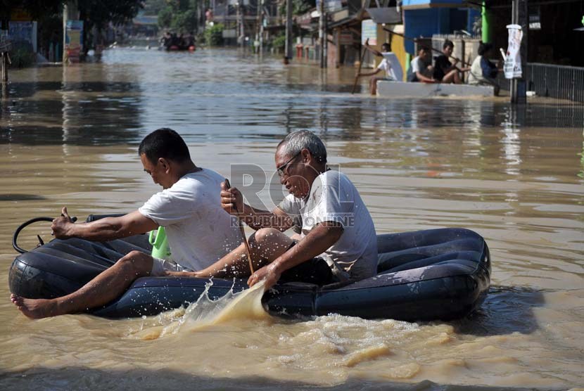  Dua orang pria melintasi genangan air banjir yang menggenangi pemukiman mereka di perumahan Pondok Gede Permai Jatiasih, Bekasi, Selasa (5/2).   (Republika/Rakhmawaty La'lang)