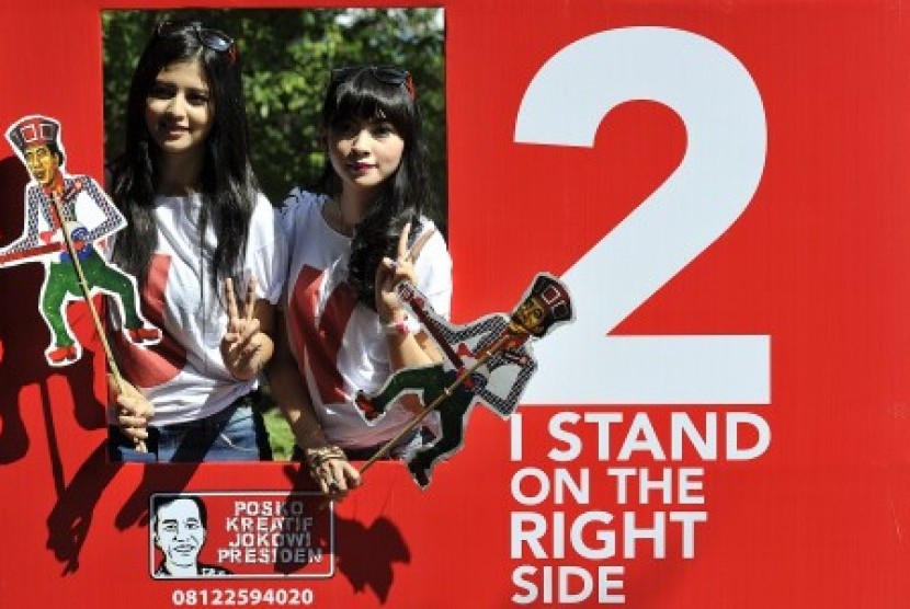 Dua orang simpatisan, Eliza (kiri) dan Friska (kanan) berpose di kotak kampanye dari calon presiden pasangan nomor urut dua, Joko Widodo di Taman Balekambang, Surakarta, Jawa Tengah, Jumat (20/6). 