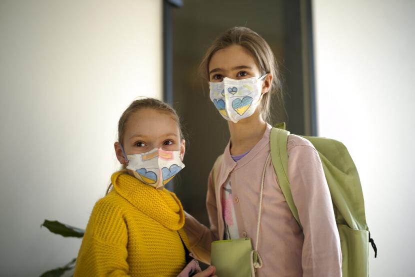 Dua orang siswa menggunakan masker yang digambar senada bendera Ukraina di Berlin, Jerman, Senin (21/3/2022). Beberapa anak pengungsi Ukraina mulai bersekolah di sekolah dasar Berlin.
