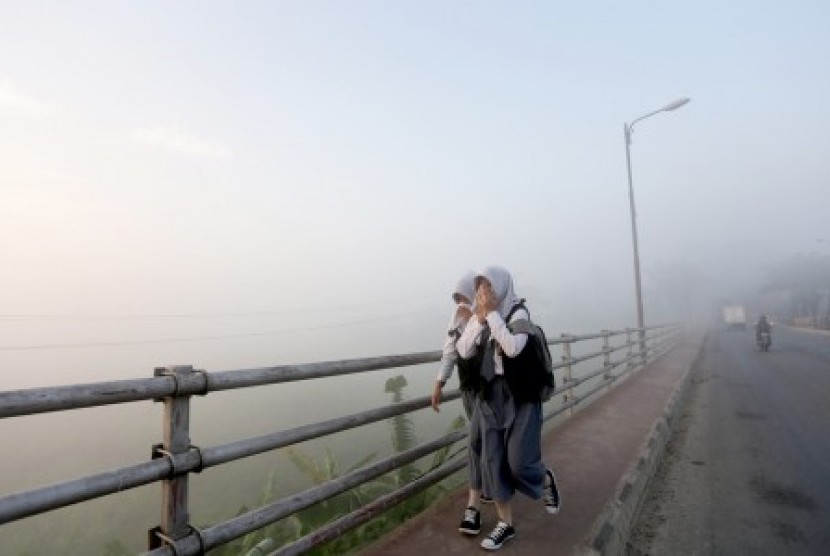 Dua orang siswa pelajar melewati kabut asap yang menutupi di jembatan Musi II, Palembang. Sumsel. Senin (31/8). 