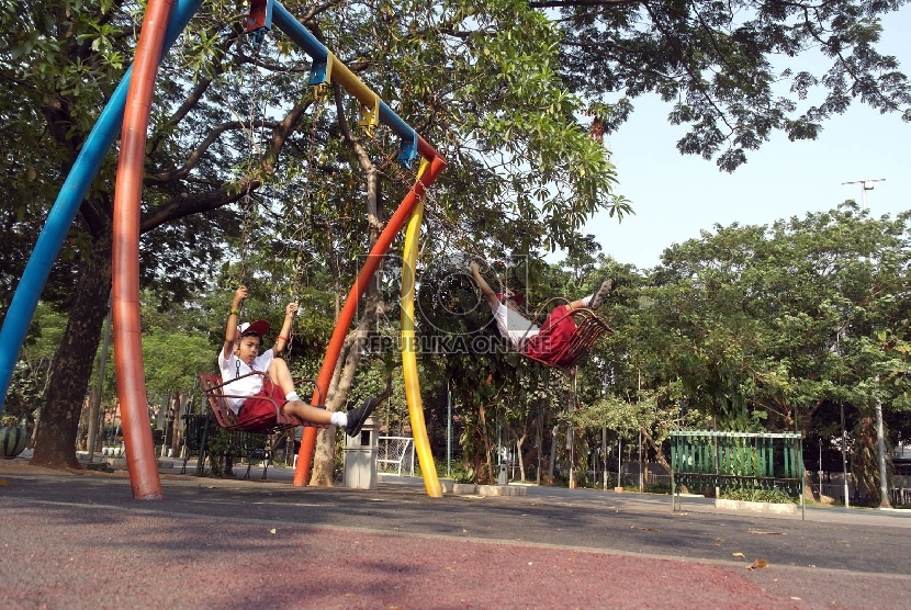 Dua orang siswa SD Nampak bermain ayunan di Taman Menteng Jakarta, Senin (5/10).