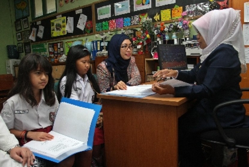 Dua orang siswa sekolah dasar negeri didampingi orang tua murid mengambil Rapor di SDN 01 Pagi Besuki Menteng, Jakarta Pusat, Senin (5/1). 