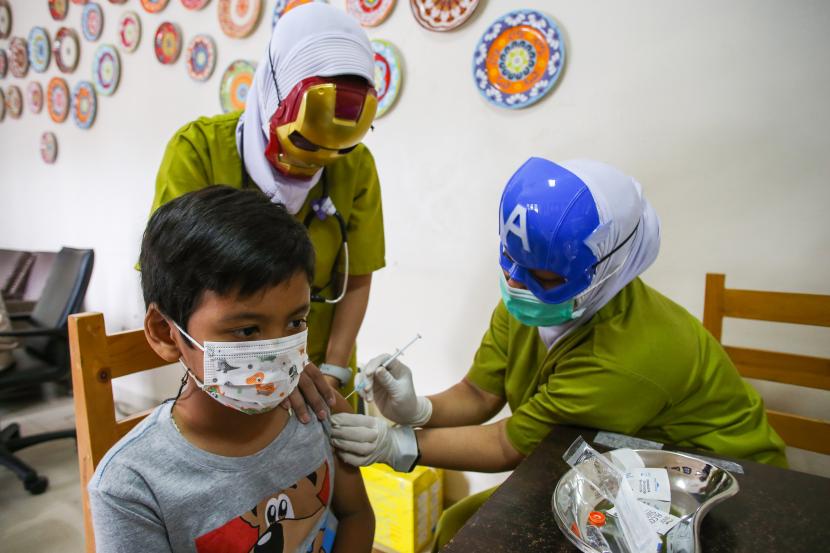 Dua orang tenaga kesehatan menggunakan topeng pahlawan super saat menyuntikkan vaksin COVID-19 kepada anak usia 6-11 tahun. Menko PMK Muhadjir Effendy meminta petugas melakukan pengecekan riwayat kesehatan anak sebelum melakukan vaksinasi.