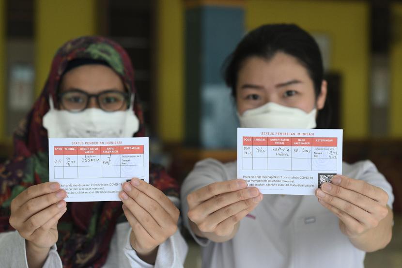Dua orang tenaga kesehatan menunjukkan kartu vaksinasi seusai menerima suntikan vaksin booster kedua di Gelanggang Remaja Pulogadung, Jakarta Timur, Senin (1/8/2022). Vaksinasi booster kedua untuk masyarakat umum baru akan dilakukan jika capaian booster pertama mencapai 50 persen dari target.