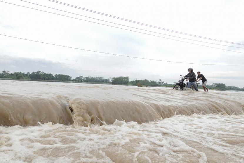 Dua orang warga menerobos banjir luapan Kali Klawing yang merendam jalur penghubung Kabupaten Banyumas-Purbalingga di Jembatan Linggamas, Desa Petir, Kalibagor, Banyumas, Jawa Tengah. (Ilustrasi)r.