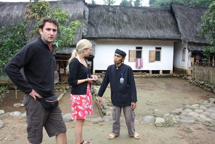 Dua orang wisatawan asing dari negara Belgia didampingi pembimbing masyarakat adat setempat berbincang-bincang tentang keberadaan Kampung Naga, di Desa Neglasari, Kecamatan Salawu, Kabupaten Tasikmalaya, Jawa Barat, Sabtu (23/7). 