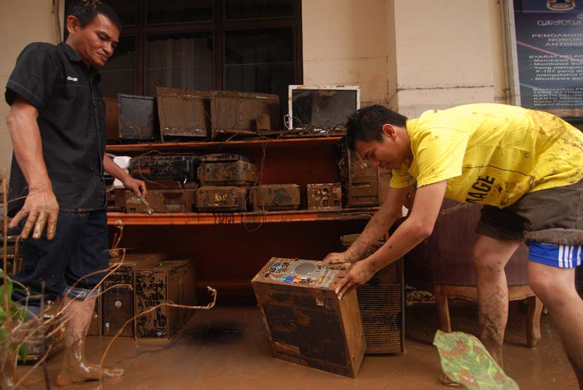   Dua pegawai membersihkan barang elektronik yang penuh lumpur akibat terendam banjir di kantor Walikota Manado, Sulawesi Utara, Kamis (16/1).    (Antara/Fiqman Sunandar)