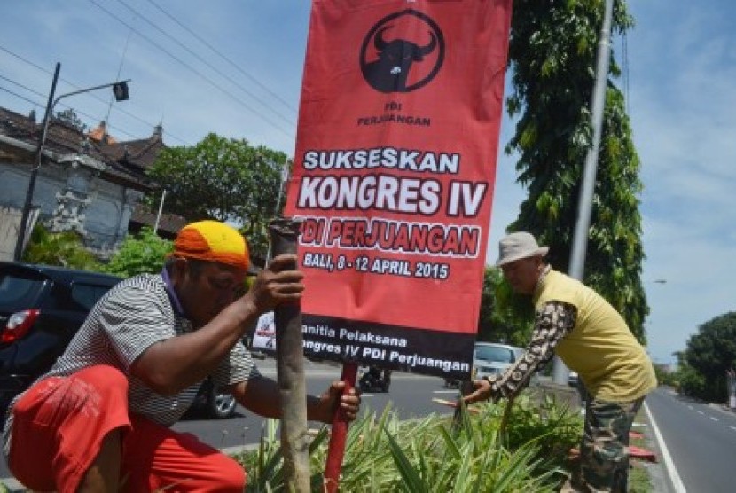 Dua pekerja memasang atribut partai PDI Perjuangan di kawasan By Pass Ngurah Rai, Sanur, Bali, Sabtu (4/4). Pemasangan atribut berupa baliho, bendera dan umbul-umbul di sejumlah kawasan di Bali tersebut dilakukan untuk menyambut Kongres PDIP yang akan dige