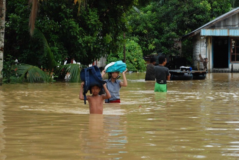 Dua pelajar berangkat sekolah melintasi banjir di Jalan Belakang Bappeda Muara Teweh Kabupaten Barito Utara, Kalimantan Tengah, Jumat (15/4).