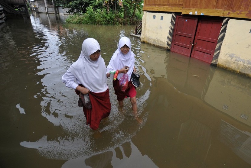 Dua pelajar berjalan menembus banjir. (Ilustrasi)