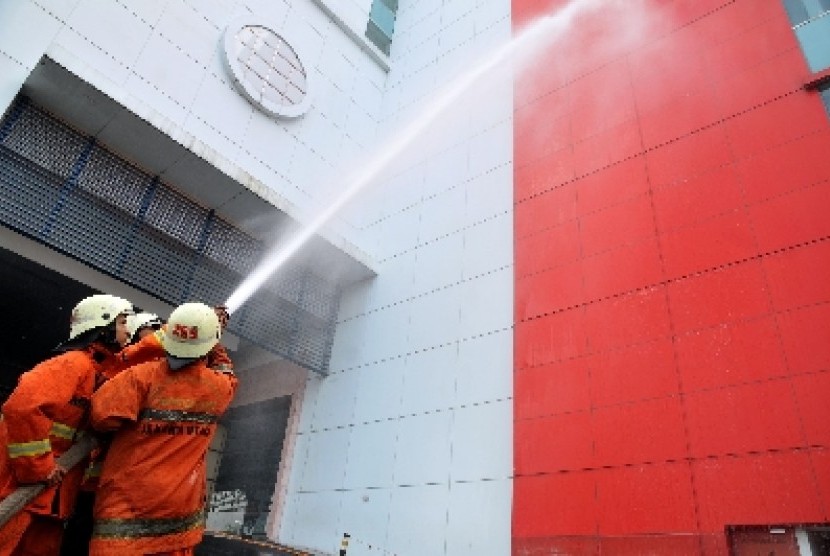 Dua pemadam kebakaran melakukan simulasi pemadaman kebakaran di sebuah gedung bertingkat di Jakarta.