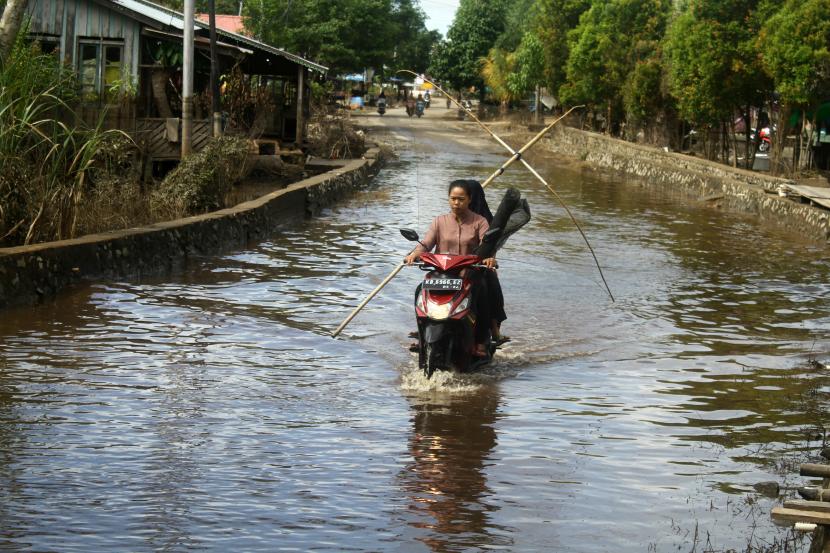 Dua pengendara motor melintasi genangan banjir (ilustrasi). Badan Nasional Penanggulangan Bencana (BNPB) memantau kejadian banjir yang merendam enam desa di Kabupaten Sintang, Kalimantan Barat sejak, Ahad (2/10/2022). 