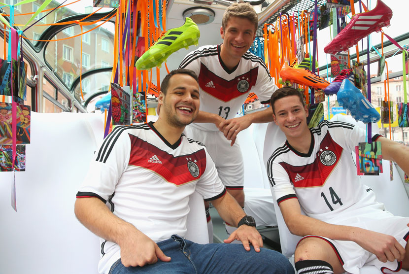 Dua penggawa timnas Jerman, Thomas Mueller (tengah) dan Julian Draxler (kanan), bersama seorang fans memperkenalkan jersey dan perlengkapan anyar timnas Jerman yang akan dikenakan pada Piala Dunia 2014 Brasil . 