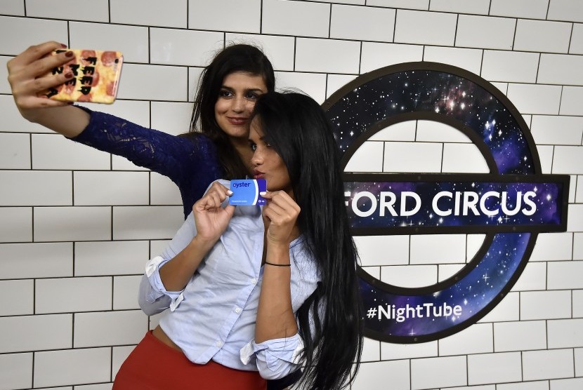 Dua penumpang London Tube berswafoto saat peluncuran Night Tube perdana di stasiun Oxford Circus.