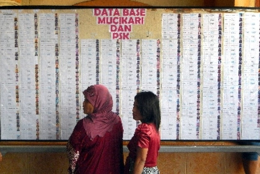Dua perempuan berada di depan papan berisi data para mucikari dan pekerja seks komersial (PSK) saat verifikasi dan sosialisasi penutupan lokalisasi di kawasan Tambakasri (Kremil) Surabaya, Jawa Timur.