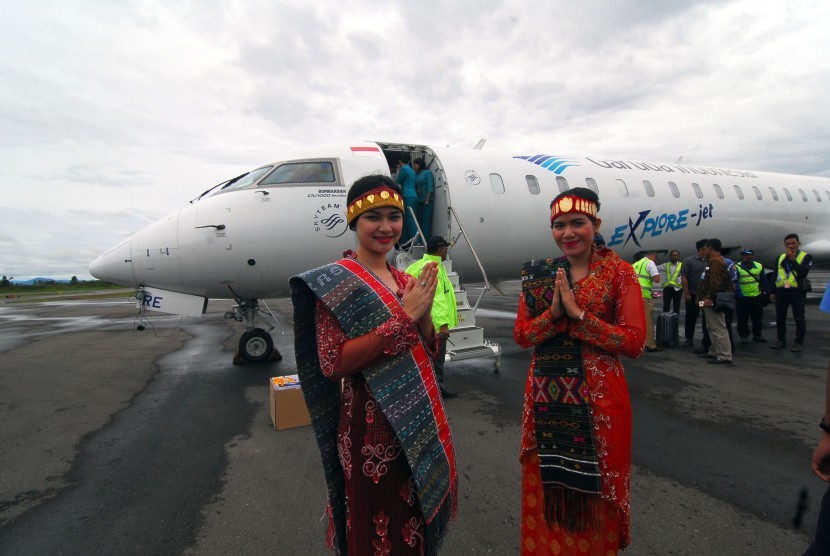 Dua perempuan berbusana daerah khas Tapanuli menyambut kedatangan pesawat CRJ 1000 milik maskapai Garuda Indonesia yang melakukan penerbangan perdana dari Jakarta ke Silangit, Tapanuli Utara, Sumatera Utara, Selasa (22/3). 