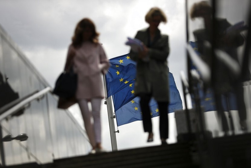 Dua perempuan berjalan dekat bendera Uni Eropa di luar markas Komisi Eropa di Brussels, Senin (27/5). Hasil pemilihan Parlemen Eropa mengakhiri dominasi partai kanan-tengah dan tengah-kiri. 