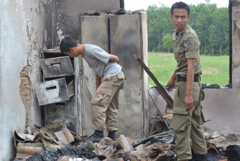  Dua personel Satpol di bekas perkantoran Pemkab Mesuji, mengais puing-puing kebakaran untuk mencari barang yang masih diselamatkan, Jumat (4/5). 