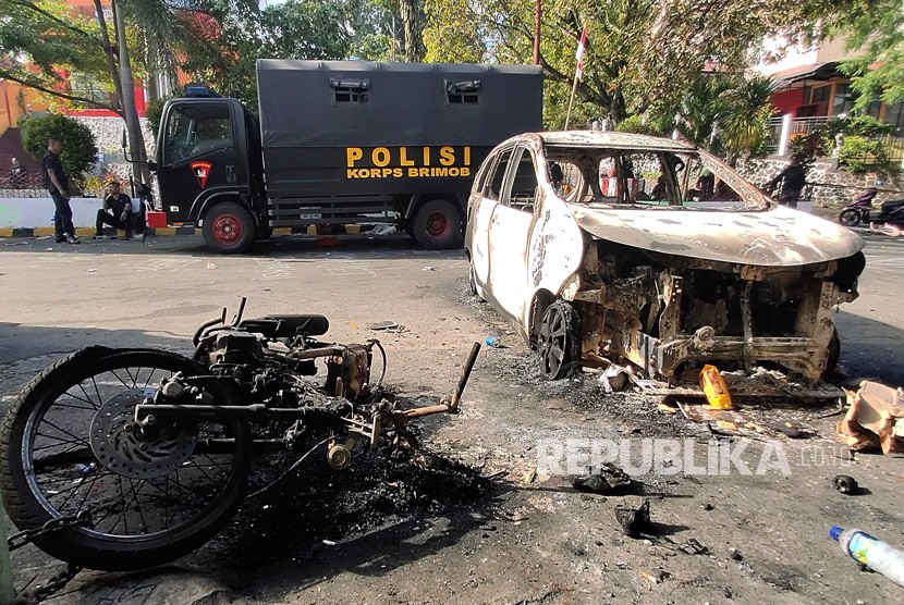 Dua personil Brimob berada di dekat kendaraan yang terbakar di Jayapura, Papua, Jumat (30/8/2019). 