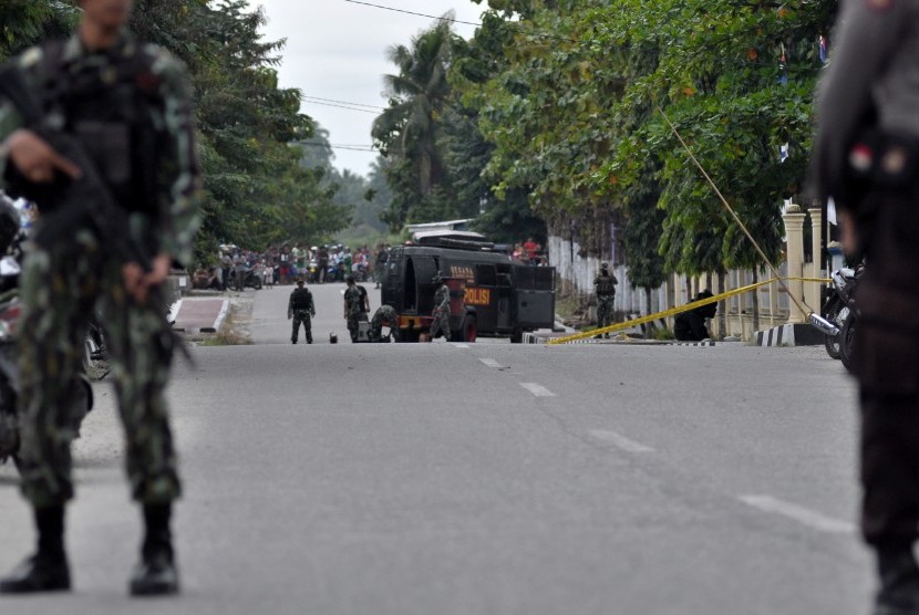 Dua personil polisi bersenjata lengkap berjaga-jaga di jalan raya tepat didepan markas Polsek Kota untuk menghalau warga sipil menuju tempat kejadian perkara (TKP) adanya benda diduga berisi bom, di Poso, Sulawesi Tengah, Rabu (11/3). 