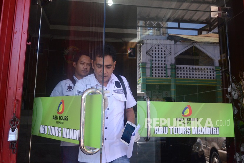 Dua petugas Direktorat Reserse Kriminal Khusus (Ditreskrimsus) Polda Sulawesi Selatan keluar ruangan usai menggeledah salah satu usaha Travel Abu Tour di jalan Baji Gau, Makassar, Sulawesi Selatan, Jumat (23/3).