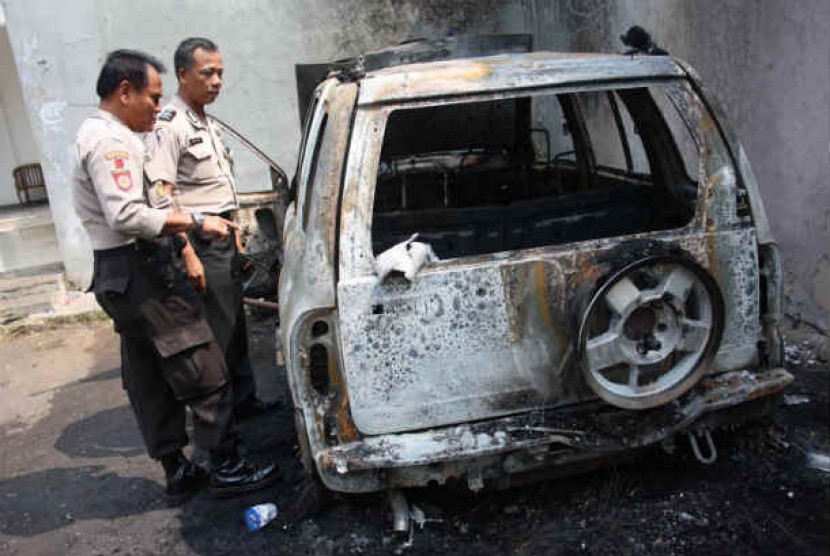  Dua petugas kepolisian melihat kondisi sebuah mobil yang habis dibakar massa di Cipadu, Tangerang, Banten, Rabu (27/6). 