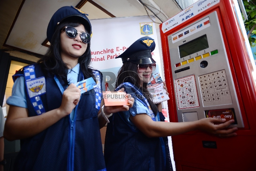 Dua petugas parkir wanita dengan mencoba kartu e-money yang digunakan untuk transaksi pembayaran pada mesin parkir meter atau Tempat Parkir Elektronik (TPE) di Jalan Agus Salim, Sabang, Jakarta Pusat, Kamis (29/1). (Republika/Raisan Al Farisi)