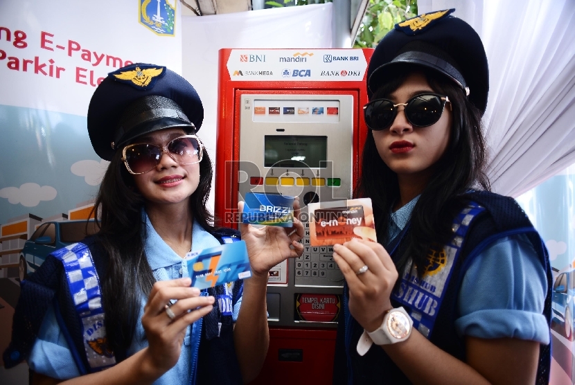 Dua petugas parkir wanita dengan mencoba kartu e-money yang digunakan untuk transaksi pembayaran pada mesin parkir meter atau Tempat Parkir Elektronik (TPE) di Jalan Agus Salim, Sabang, Jakarta Pusat, Kamis (29/1). (Republika/Raisan Al Farisi)