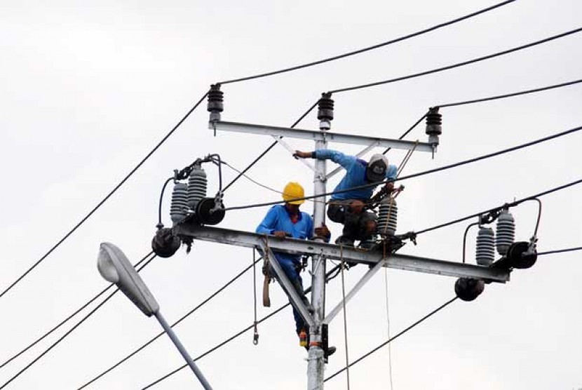 Dua petugas PT PLN tengah melakukan perbaikan jaringan listrik.
