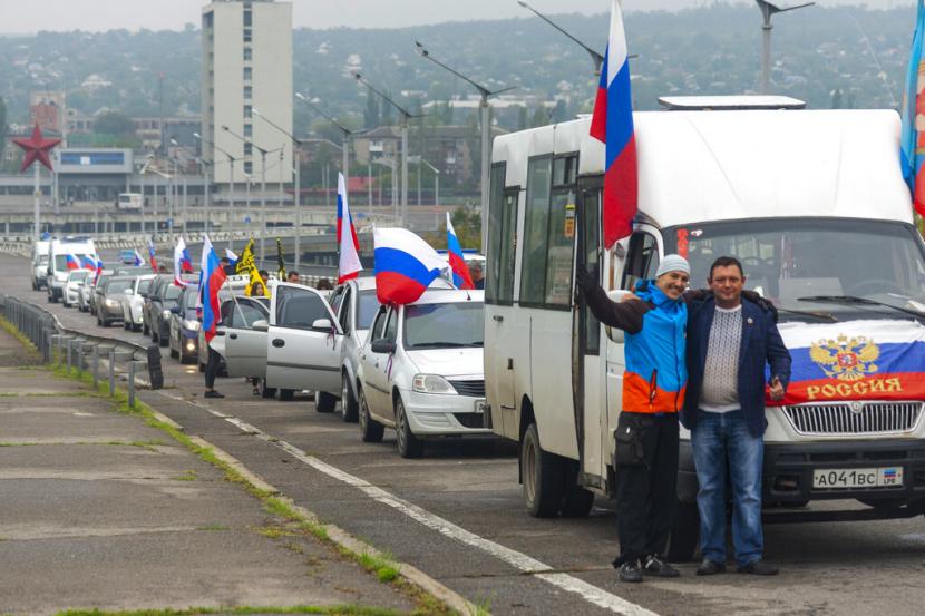 Dua pria berpose untuk foto di depan iring-iringan mobil yang diselenggarakan untuk mendukung pemungutan suara dalam referendum di Luhansk, Ukraina timur, Jumat, 23 September 2022. Pemungutan suara dimulai Jumat di empat wilayah Ukraina yang dikuasai Moskow mengenai referendum untuk menjadi bagian dari Rusia