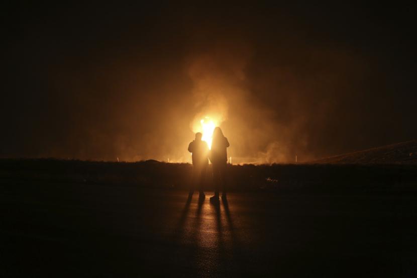 Dua pria melihat api setelah pipa gas alam meledak di luar kota Boroujen di provinsi Chaharmahal barat dan Bakhtiari, Iran, pada Rabu pagi, 14 Februari 2024. Ledakan melanda pipa gas alam di Iran Rabu pagi, dengan seorang pejabat menyalahkan ledakan tersebut sebagai akibat dari 