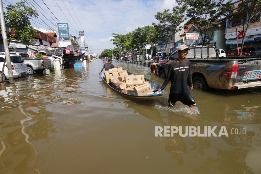 Dua pria menarik perahu saat banjir di Samarinda, Kalimantan Timur.