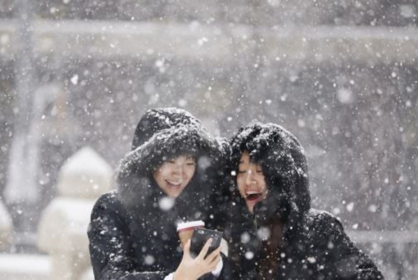 Dua remaja menikmati hujan salju di Seoul