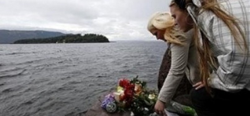 Dua remaja Norwegia menghanyutkan karangan bunga di pantau Pulau Utoya sebagai simbol duka