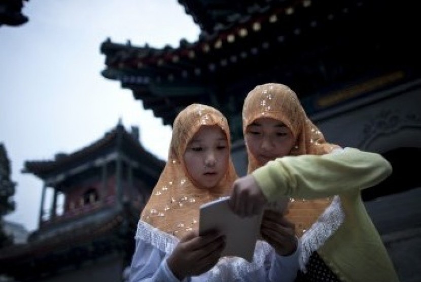 Dua remaja putri membaca Alquran di kompleks Masjid Niujie, Beijing, sembari menunggu waktu berbuka puasa.